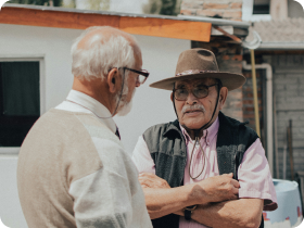 two Mexican men standing outside talking with one another