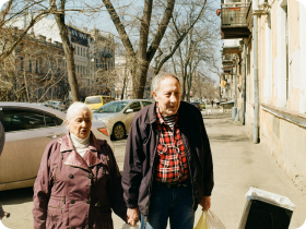 an European elderly couple walking in the city holding hands and carrying groceries