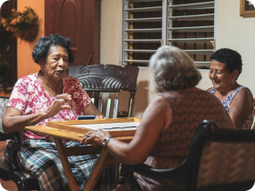 small group of hispanic women playing a game around a square table